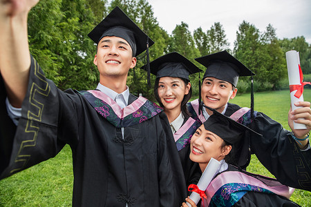 高等教育四个身穿学士服的大学生扶着镜头一起自拍青年女人高清图片素材