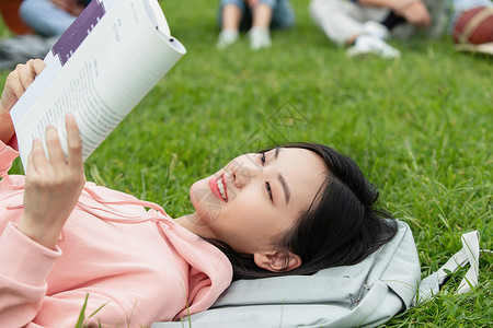课余活动女大学生躺在草地上看书背景