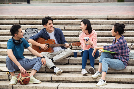 青年伴侣耳机女人年轻的大学生坐在台阶上弹吉他唱歌图片