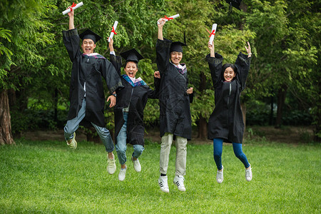 草地大学生穿着学士服庆祝毕业休闲活动高清图片素材