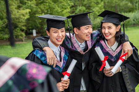 草地搂着三个人户外穿着学士服的大学生们高等教育高清图片素材