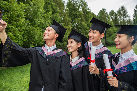 四个身穿学士服的大学生用手机自拍高清图片