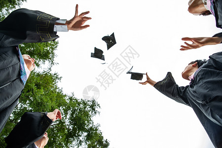 高举学士帽穿着学士服的大学生扔学士帽背景