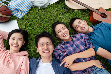 四个人快乐的大学生躺在草地上图片素材