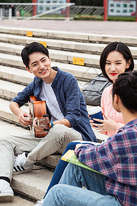 年轻的大学生坐在台阶上弹吉他唱歌图片