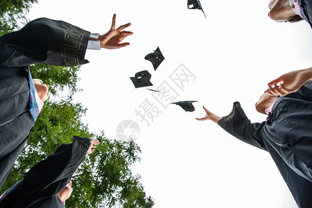 高举学士帽典礼穿着学士服的大学生扔学士帽背景