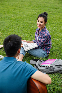 面对面女朋友人快乐的女生坐在草地上听同学弹吉他图片