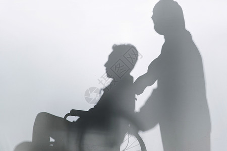 两个人剪影医务工作者推着坐轮椅的患者背景