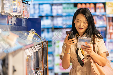 药店活动素材中年女在超市挑选商品背景