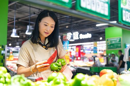 欢乐促销中年女在超市挑选蔬菜背景