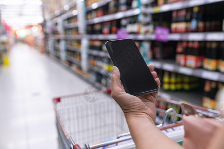 超市便利中年女拿着手机在超市购物背景