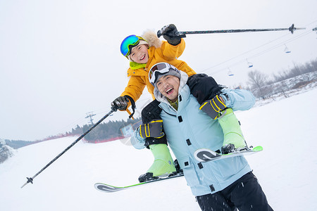 父亲骑车带小孩滑雪场上拿滑雪杖的快乐男孩骑在父亲脖子上背景