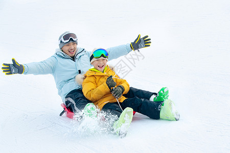 小孩坐着兴奋无忧无虑厚衣服快乐父子坐着雪上滑板滑雪背景