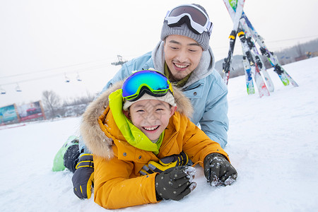 疼的打滚滑雪场内抱在一起打滚的快乐父子背景