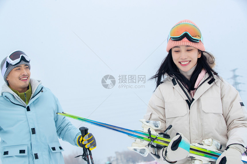 拿着滑雪板滑雪杖的快乐情侣图片