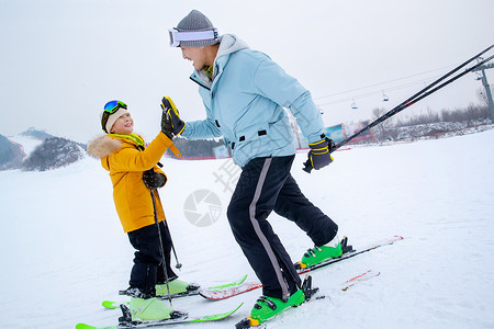 雪滑滑雪场上滑着雪击掌的快乐父子背景