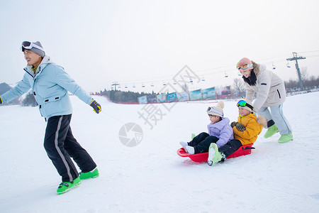 带儿子女儿冬日滑雪的父母白昼高清图片素材