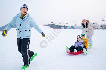 滑滑板的男孩带儿子女儿冬日滑雪的父母背景