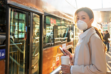 汽车问题防疫戴口罩的年轻女人站在公交车站背景