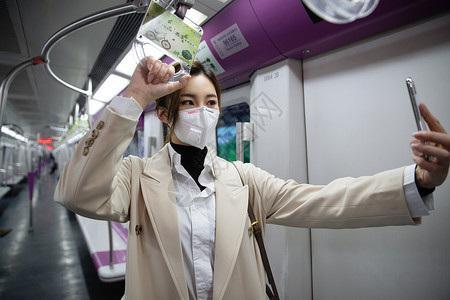 戴口罩的年轻女人在地铁里看手机图片