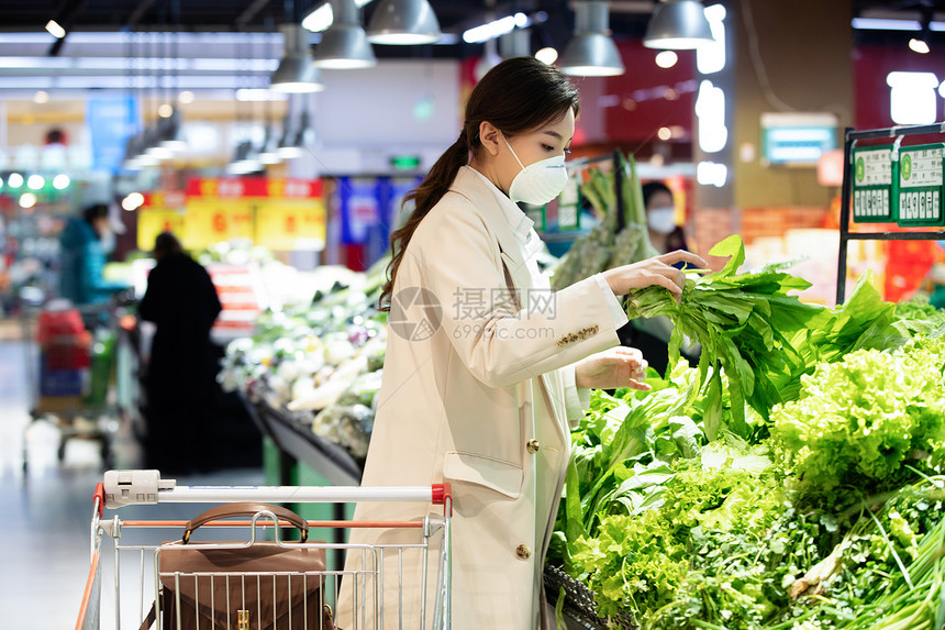 戴口罩的青年女人在超市购买青菜图片
