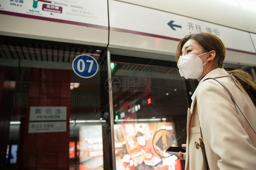 城市生活戴口罩的年轻女人站在地铁站台上图片