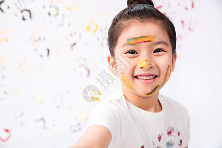 彩色油漆痕迹效果痕迹表现积极人脸上涂满颜料的小女孩背景