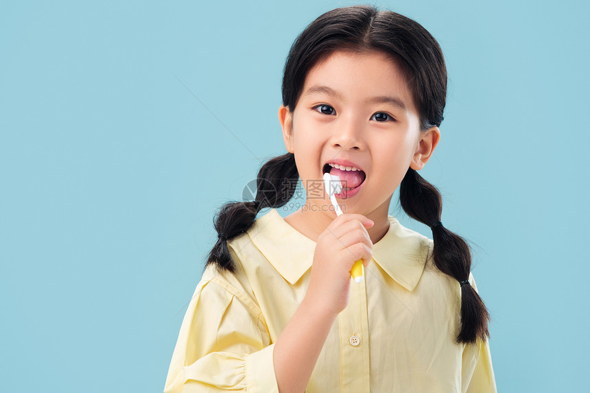 东方人享乐注视镜头拿着牙刷刷牙的小女孩图片