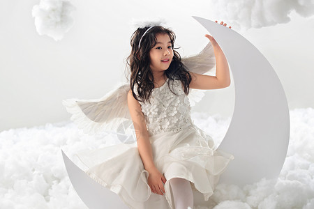 月亮上小天使可爱的裙子微笑坐在月亮上的快乐小天使背景
