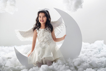月亮上小天使云影棚拍摄摄影坐在月亮上的快乐小天使背景