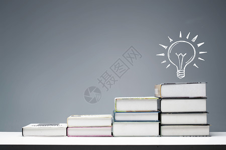 书创意摄影插画桌子上叠摞的书和灯泡图像背景