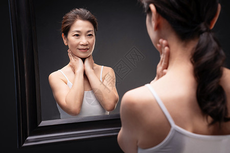照镜子按摩颈部的中年女人图片