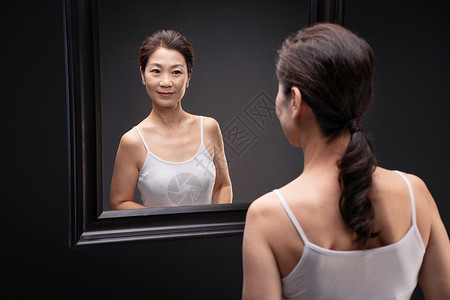 中年女欣赏镜子中的自己吊带高清图片素材