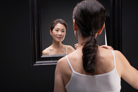 中年女人欣赏镜子中的自己护肤高清图片素材