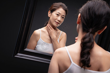 中老年女人对着镜子做颈部护理图片