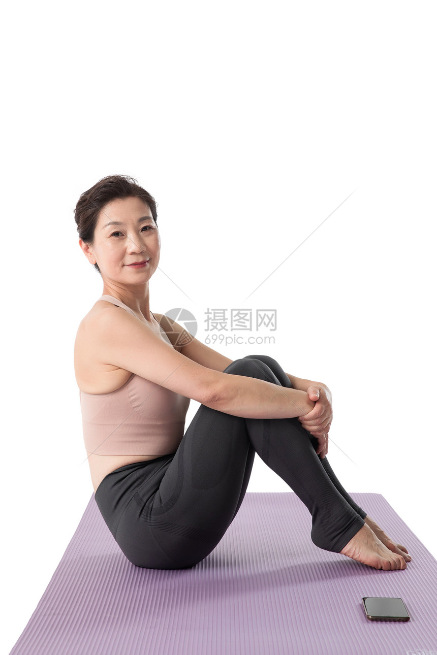 坐在瑜伽垫上休息的中老年女人图片