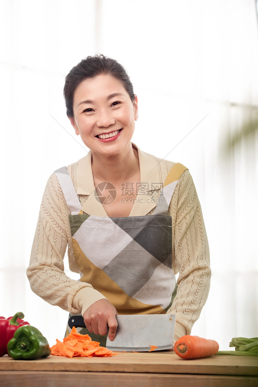 厨房内切菜的中年女人图片