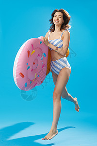 休闲兴奋青年人抱着冰淇淋形状的浮排跳跃的泳装美女图片
