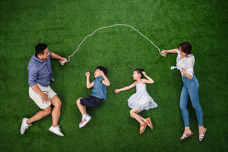 两个孩子的家庭侧卧爱快乐的一家四口在草地上跳绳背景