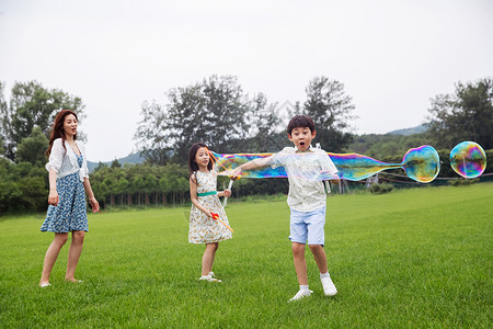 减压青年女人单亲家庭妈妈带着两个孩子在草地上快乐玩耍图片