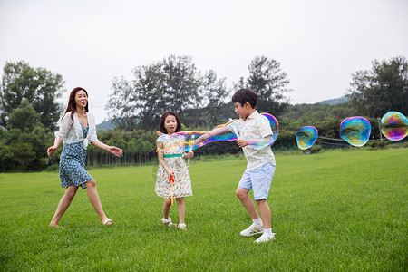 微笑无忧无虑兴奋妈妈带着两个孩子在草地上快乐玩耍高清图片