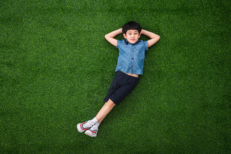 可爱的小男孩躺在草地上高清图片