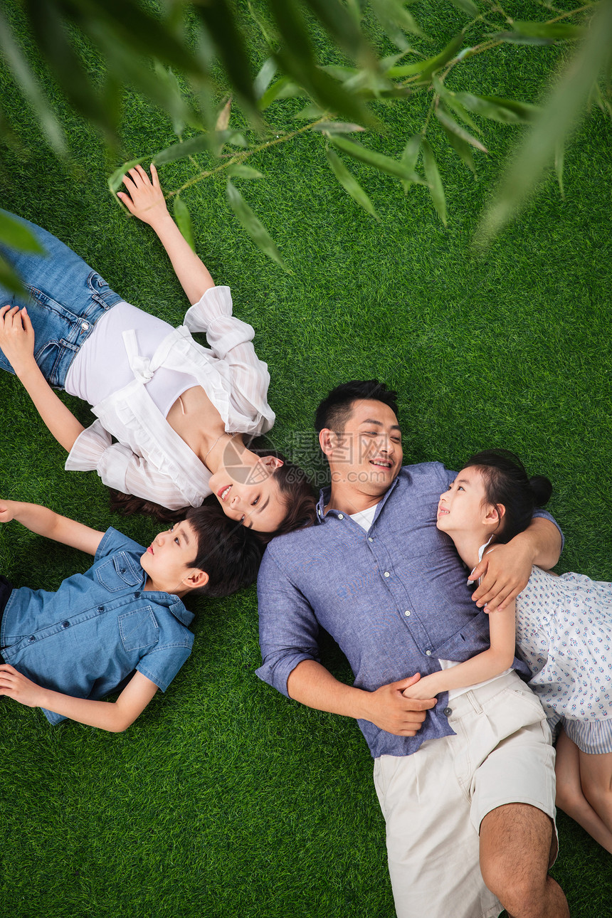 无忧无虑周末活动躺着幸福的一家四口躺在草地上图片