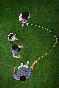 玩耍亚洲不看镜头快乐的一家四口在草地上跳绳背景
