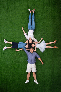 青年人兄弟姐妹四个人幸福的一家四口头挨着头躺在草地上图片
