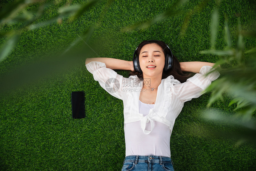 躺着彩色图片东方人躺在草地上听音乐的青年女人