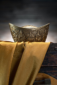 中国传统年画金子储蓄静物木箱上的金缎和金元宝背景
