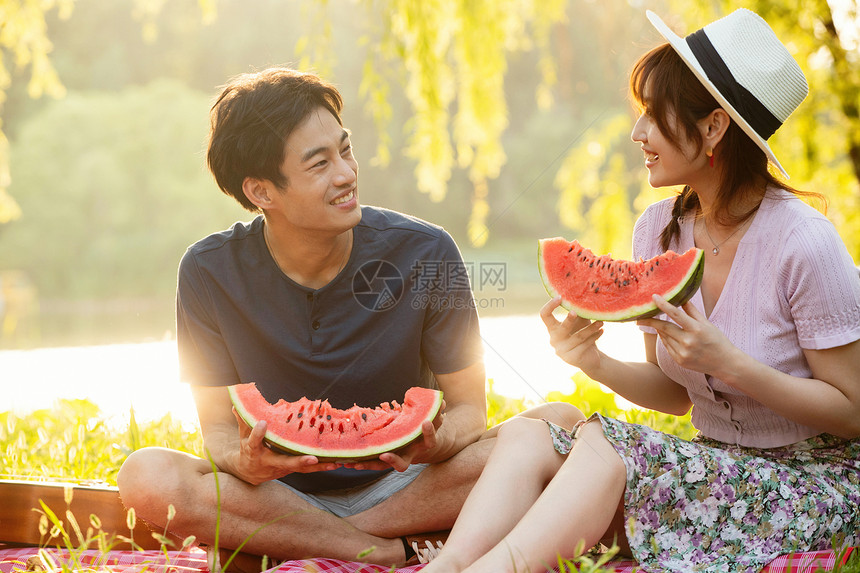 活力青年夫妇无忧无虑坐在草地上吃西瓜的幸福情侣图片
