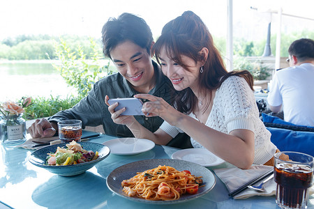 用手机拍美食的快乐情侣背景图片