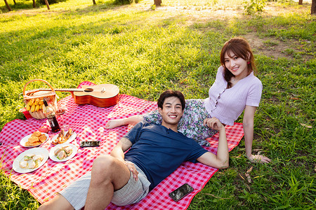 躺着约会的情侣倚靠欢乐香蕉躺在草地上的幸福情侣背景
